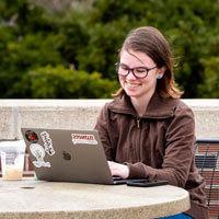 Student works on her laptop at a table outside.